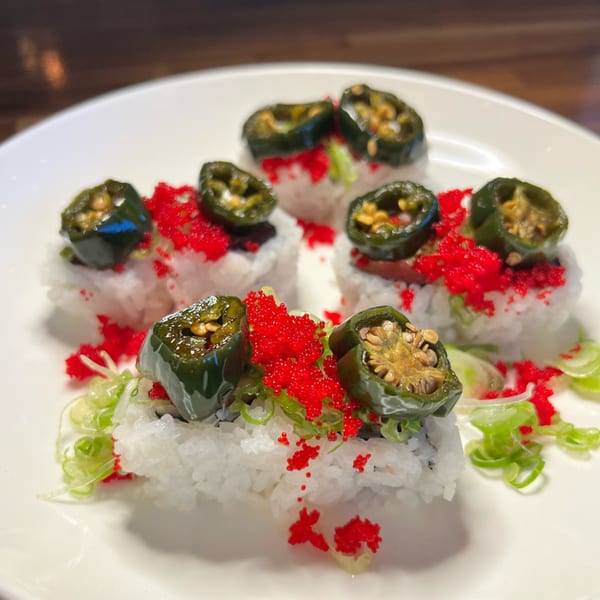Tsunami Panhandle sushi rolls topped with sliced jalapeños, red roe, and green onions on a white plate.
