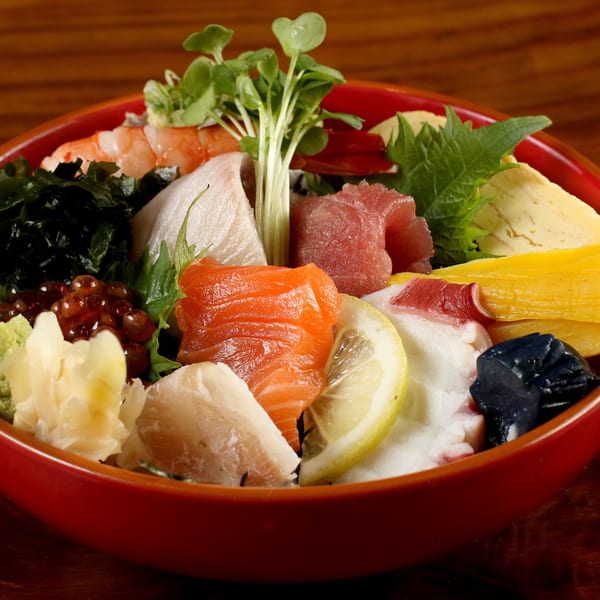 A vibrant chirashi bowl from Tsunami Panhandle, featuring various sashimi, roe, and garnishes.