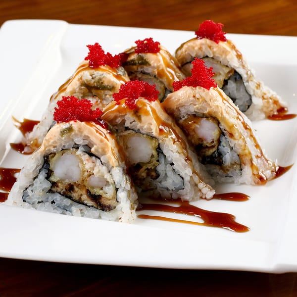 Tsunami Panhandle sushi rolls with shrimp tempura, sauce, and red tobiko on a white plate.